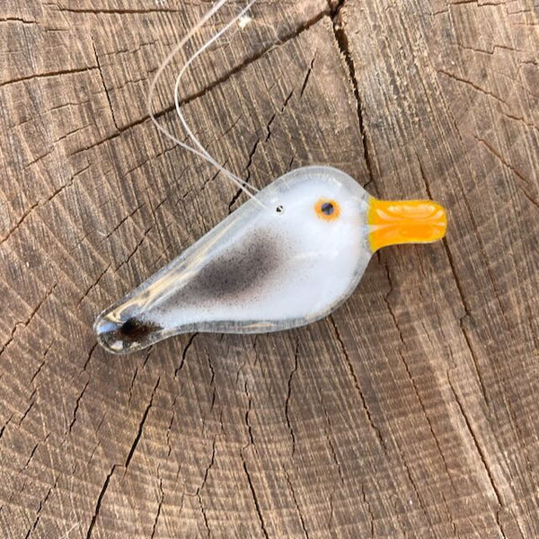 Load image into Gallery viewer, Handcrafted grey and white Fused Glass Pocket Seagull displayed against a log