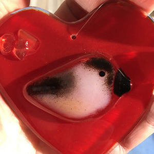 A close up of a red Fused Glass Heart with Chickadee in Hand