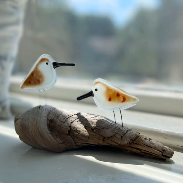 Load image into Gallery viewer, A pair of glass sandpiper chicks sit on a driftwood log. The backdrop is out of focus