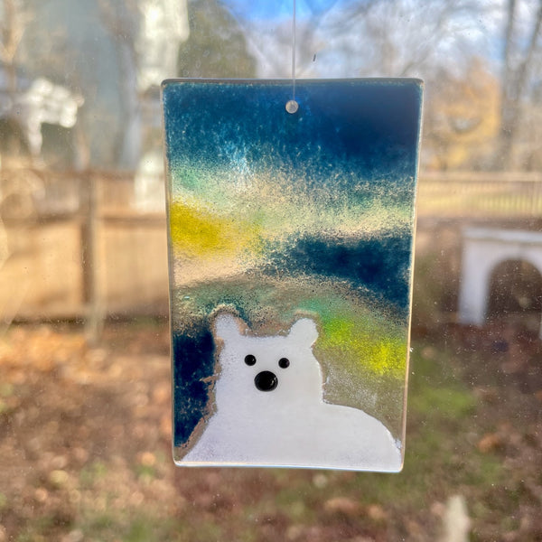 Load image into Gallery viewer, A glass sun catcher featuring the head and shoulders of a white polar bear. The background of the tile is a midnight blue sky with lemon and aqua aurora borealis.