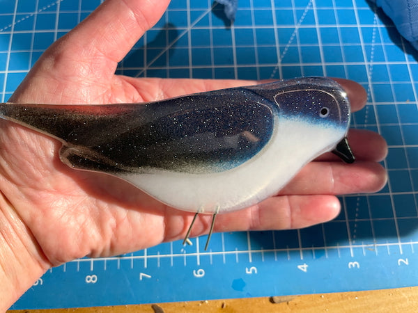 Load image into Gallery viewer, A blue and white glittery fused glass adult tree swallow, held in the hand for scale