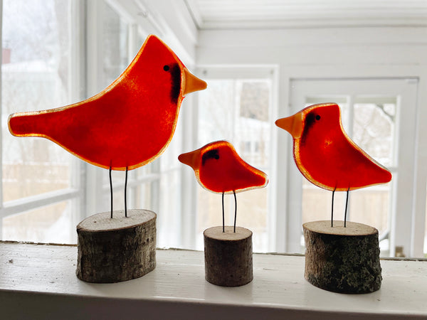 Load image into Gallery viewer, Three red bird figurines on wooden bases in a bright room with large windows.
