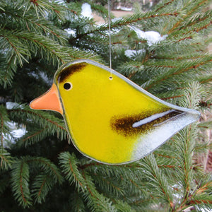 Yellow bird-shaped ornament hanging on a tree branch