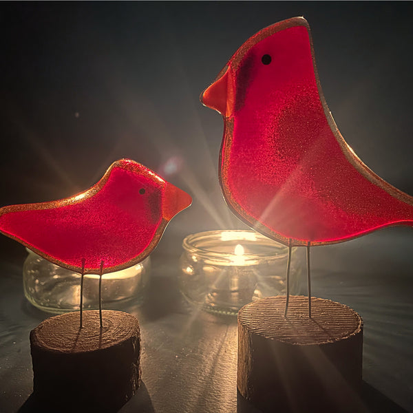 Charger l'image dans la galerie, Two glass red cardinal birds on log stands in front of a tabletop romantic candlelight scene
