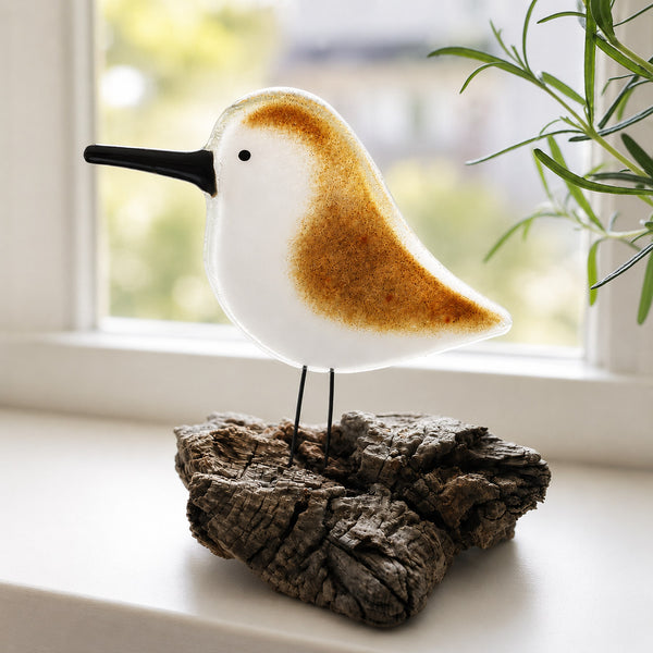 Load image into Gallery viewer, Glass sandpiper figurine on a wooden base in front of a window with greenery
