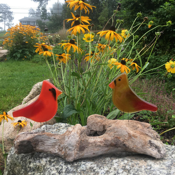 Load image into Gallery viewer, A pair of male and female cardinals made of glass, perch on driftwood in a garden in front of some Black-eyed Susan flowers