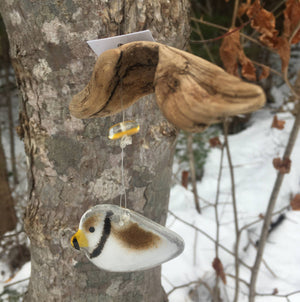 Glass Brown Bird with Yellow Beak hanging from a piece of driftwood.