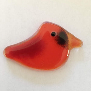 a small red fused glass bird faces right
