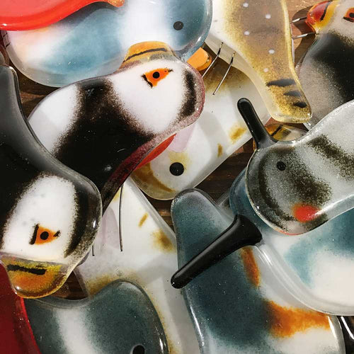 A close up picture of assorted glass birds of various colours