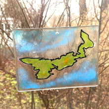 Load image into Gallery viewer, A rectangular glass sun catcher featuring the shape of Prince Edward Island in green and outlined in black. The background glass is blue to represent the sea.
