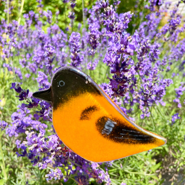 Load image into Gallery viewer, Decorative orange and black bird-shaped glass ornament in front of lavender flowers
