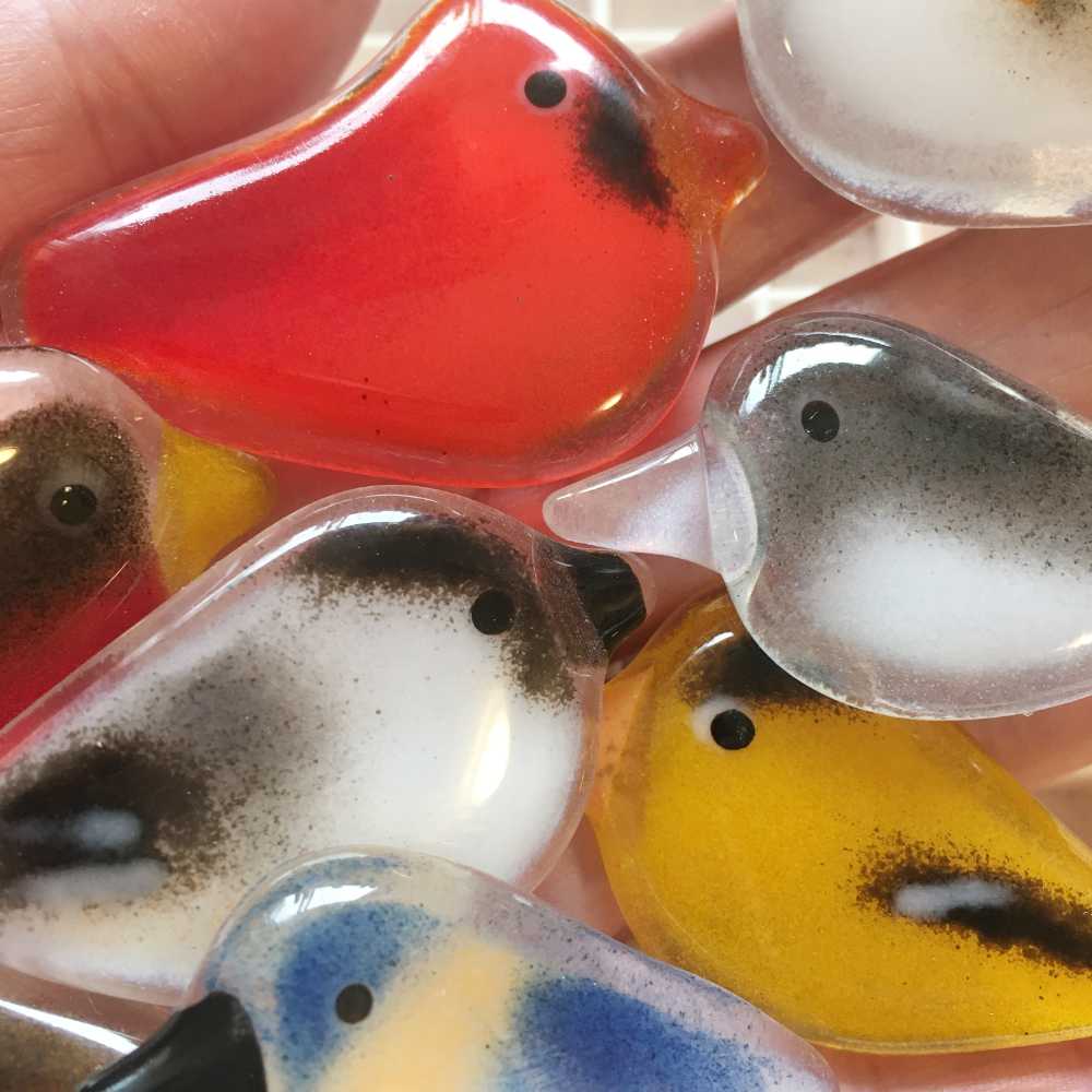 A close up of assorted fused glass pocket birds