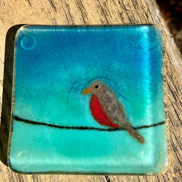 Charger l&#39;image dans la galerie, A blue and turquoise green fused glass coaster featuring a robin on a black wire. 
