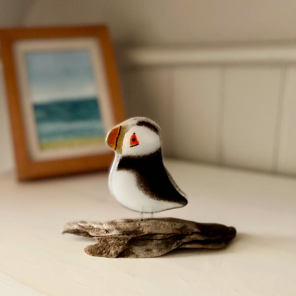 Load image into Gallery viewer, A black, white and orange fused glass Puffin Chick perched on driftwood - bathroom decor
