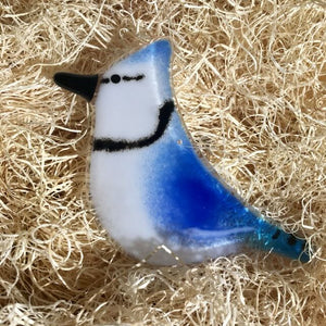 A close up of a blue and white glass bluejay ornament  in nesting packaging material