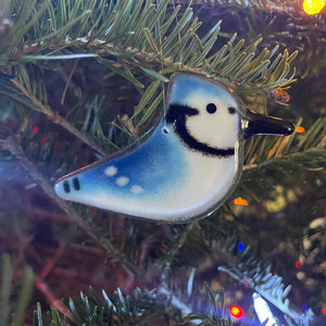 Decorative bird ornament on a Christmas tree with lights in the background