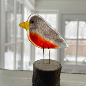 Brown and red transparent fused glass robin perched on a log in a window sill