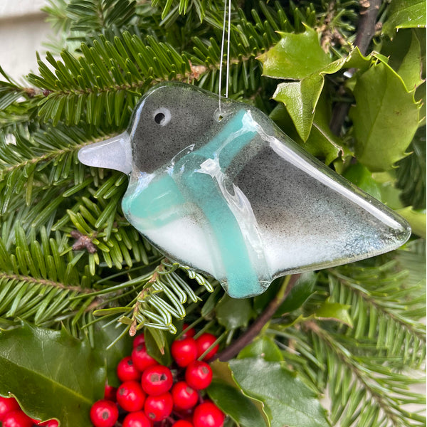Load image into Gallery viewer, Glass Junco bird ornament on a Christmas tree with green leaves and red berries
