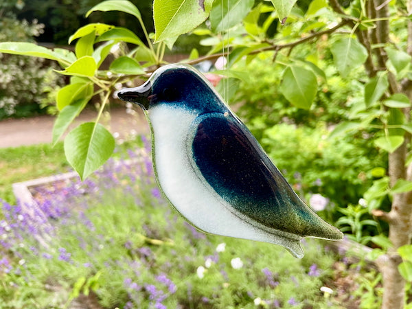 Load image into Gallery viewer, Deep Blue and White Fused Glass Tree Swallow Ornament Hanging in the Backyard Garden

