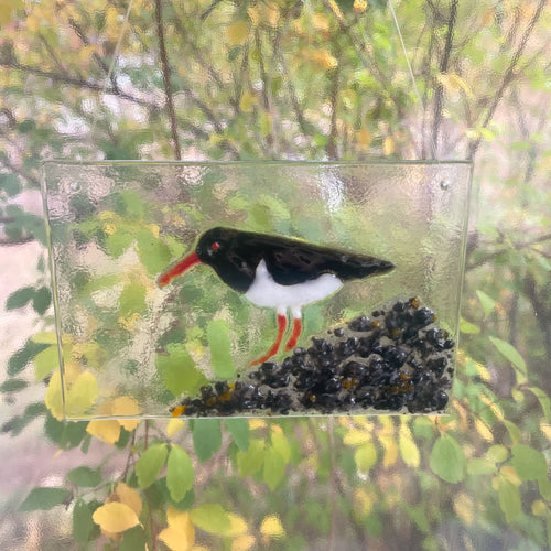 Decorative glass panel with a bird design on a natural background