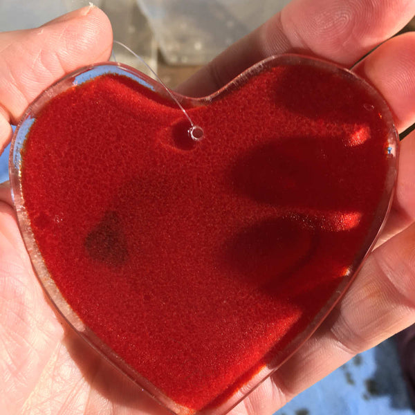 Load image into Gallery viewer, A Fused Glass Heart with Chickadee being held in a hand in Reverse
