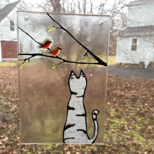 A Fused Glass Painting Tile featuring a grey and black tabby cat with a robin in a tree