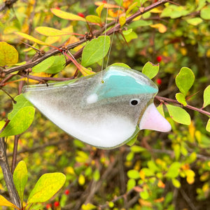 handcrafted fused glass junco in a blue hat against a natural background