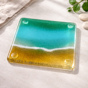 Glass coaster with beach design on a light surface