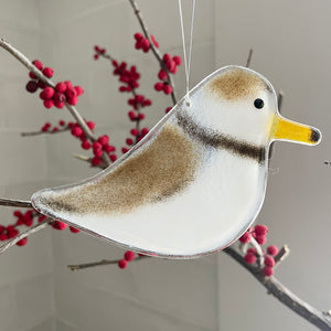 Decorative Piping Plover glass bird ornament with a yellow beak on a branch with red berries.