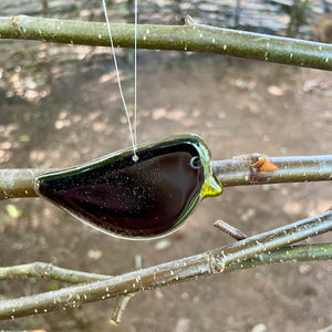 Hanging fused glass blackbird chick on a branch