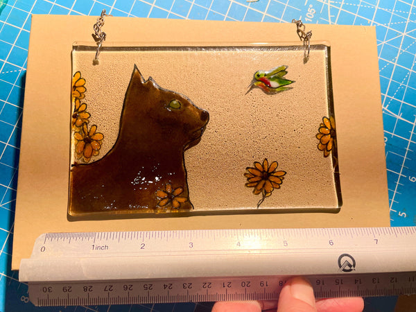 Load image into Gallery viewer, Glass panel with a cat design and flowers, held up against a ruler for size reference.
