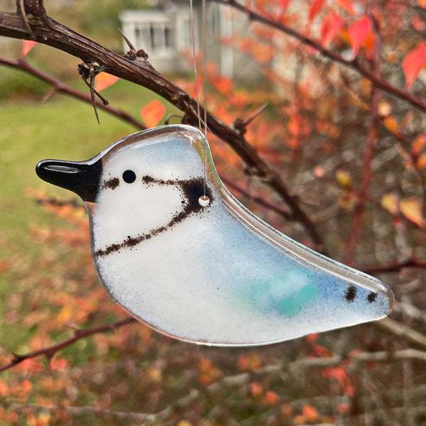 Charger l&#39;image dans la galerie, Glass bluejay bird ornament hanging on a branch with autumn leaves in the background
