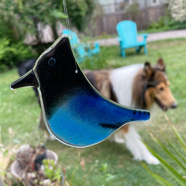 Load image into Gallery viewer, Blue glass bird ornament with a dog in the background
