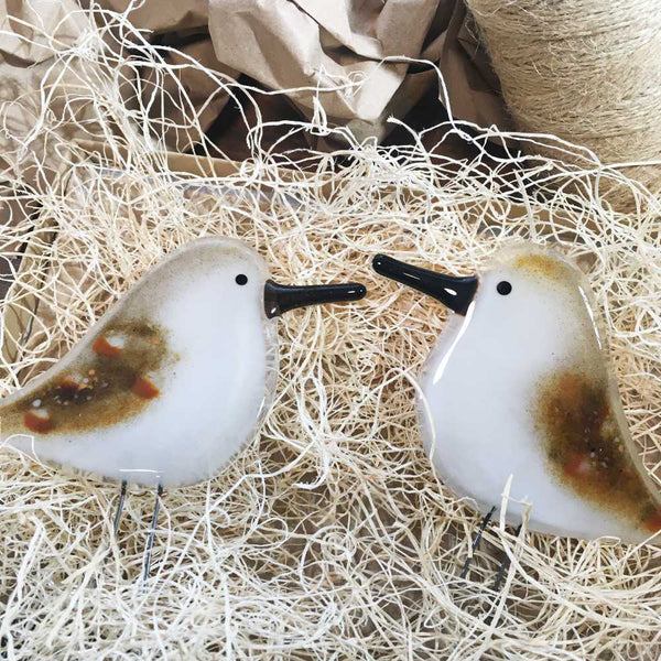 Charger l&#39;image dans la galerie, Two brown speckled and white glass birds with long black beaks, shaped to look like sandpipers. The two birds have been placed on wood fibre nesting material.
