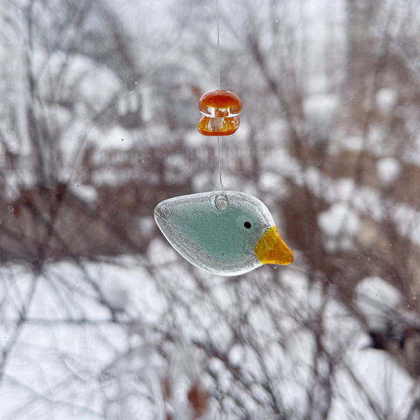 Load image into Gallery viewer, Fused glass aqua bird ornament hanging against a snowy background

