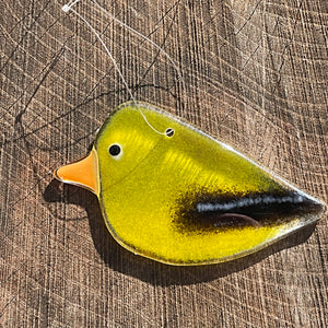 Yellow glass female goldfinch bird ornament on a wooden surface