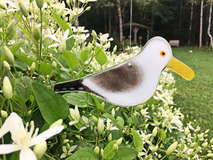 fused glass seagull hanging amongst flowers