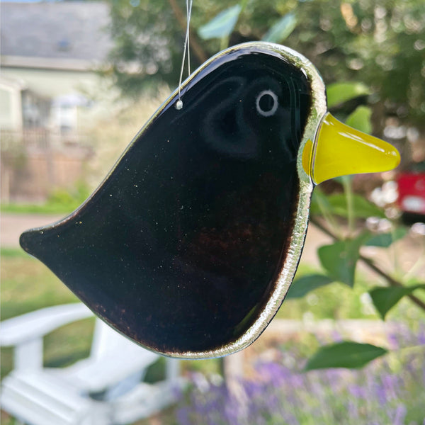 Load image into Gallery viewer, a black fused glass blackbird ornament hangs in front of a natural backdrop
