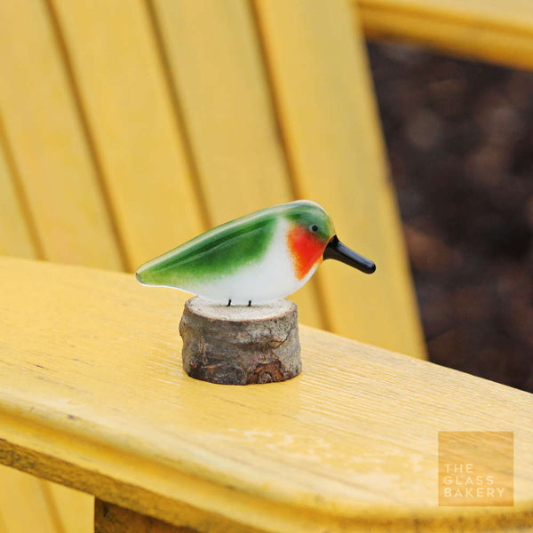 Load image into Gallery viewer, a red and green ruby throated hummingbird sits on a log. the log is on a bright gold painted Adirondack chair
