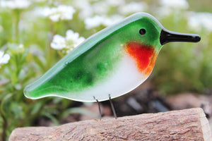 a fused glass ruby throated hummingbird sits on a log