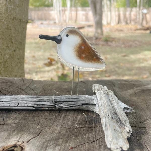 Load image into Gallery viewer, fused glass brown and white speckled sandpiper bird ornament perched on driftwood and resting on a log in woodland garden
