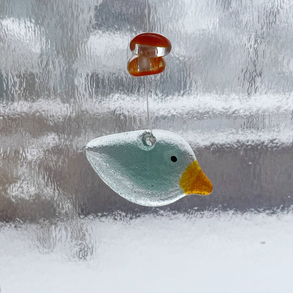 Load image into Gallery viewer, Glass blue seafoam bird decoration hanging on a window with a blurred background
