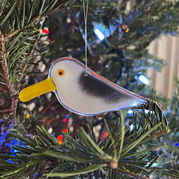 Load image into Gallery viewer, Glass bird ornament hanging on a Christmas tree with blurred lights in the background
