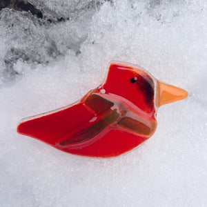 Red glass bird ornament on a snowy background