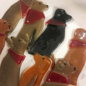 A collection of brown and black glass dog ornaments, wearing red bandanas