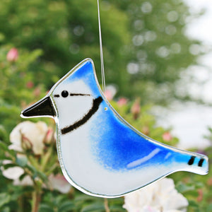 Glass Hanging Blue Jay Ornament against a back drop of pink dog roses