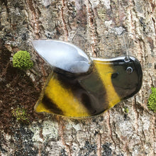 Load image into Gallery viewer, Close up image of a glossy black and gold glass bee with white wing. The bee is hanging in front of a tree.

