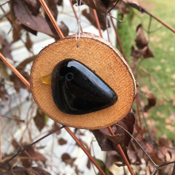 Load image into Gallery viewer, A small black glossy glass bird mounted on a slice of log - hanging ornament
