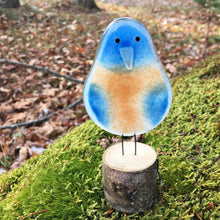 Load image into Gallery viewer, bluebird chick - blue and peachy orange coloured glass bird on log perch. The background is a mossy rock and autumn leaves.
