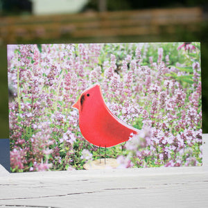A picture of a birthday card featuring a red cardinal in purple flowers.